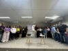 Fotografia colorida mostrando parte do público participante do evento. As pessoas estão de pé, no palco e ao fundo aparece imagem indicando ser o II encontro da Estatuinte.