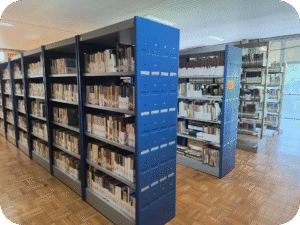 Fotografia colorida mostrando imagem onde aparecem 3 corredores de estantes com livros.